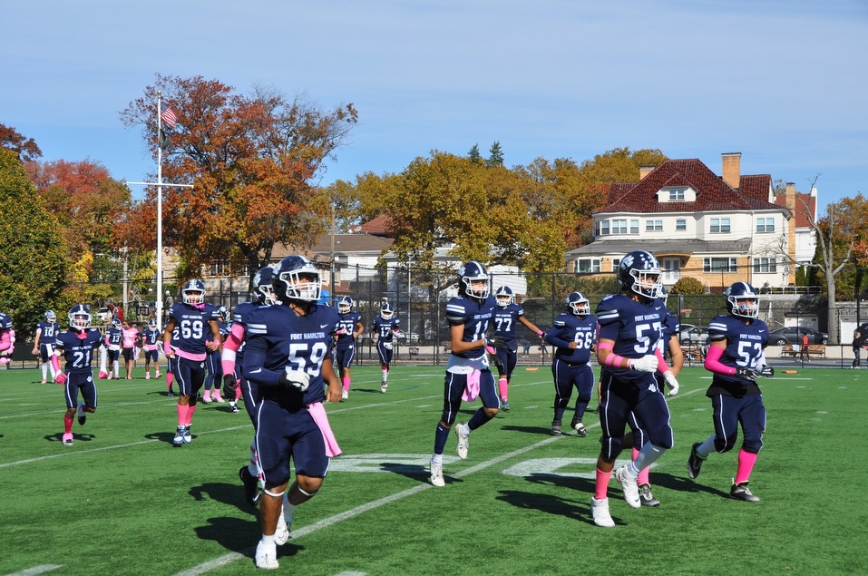 Players run onto the field wearing pink accessories in support of Breast Cancer Awareness Month.